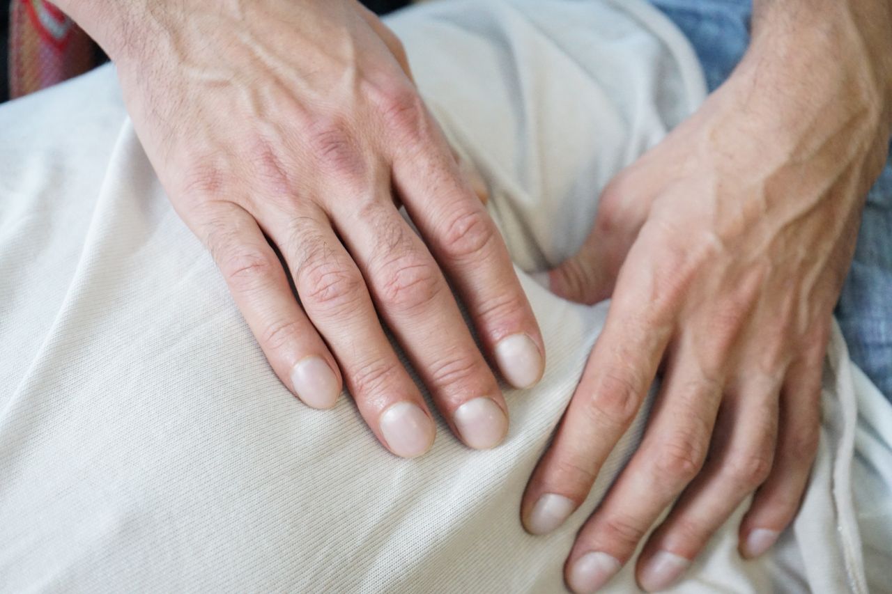 our-experience Detailed view of hands giving a soothing massage on a white fabric indoors. Perfect for wellness themes.