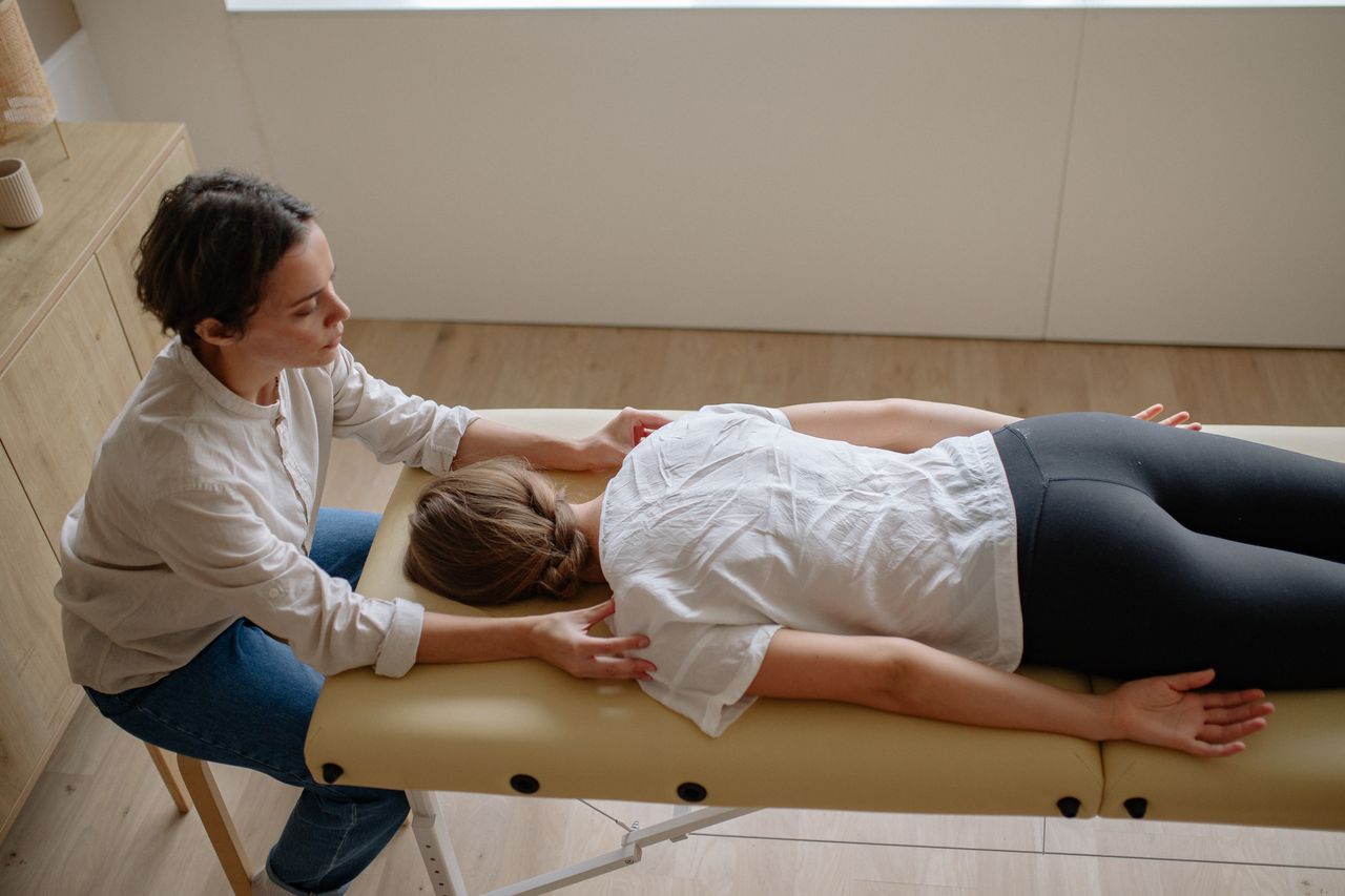 services-01 A therapist performs a chiropractic adjustment on a woman lying on a treatment table indoors.